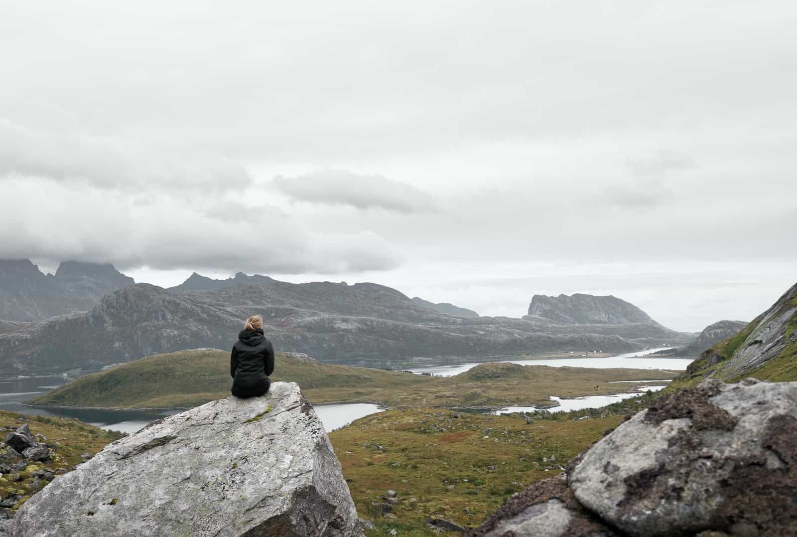 woman sitting on gray rock formation during daytime