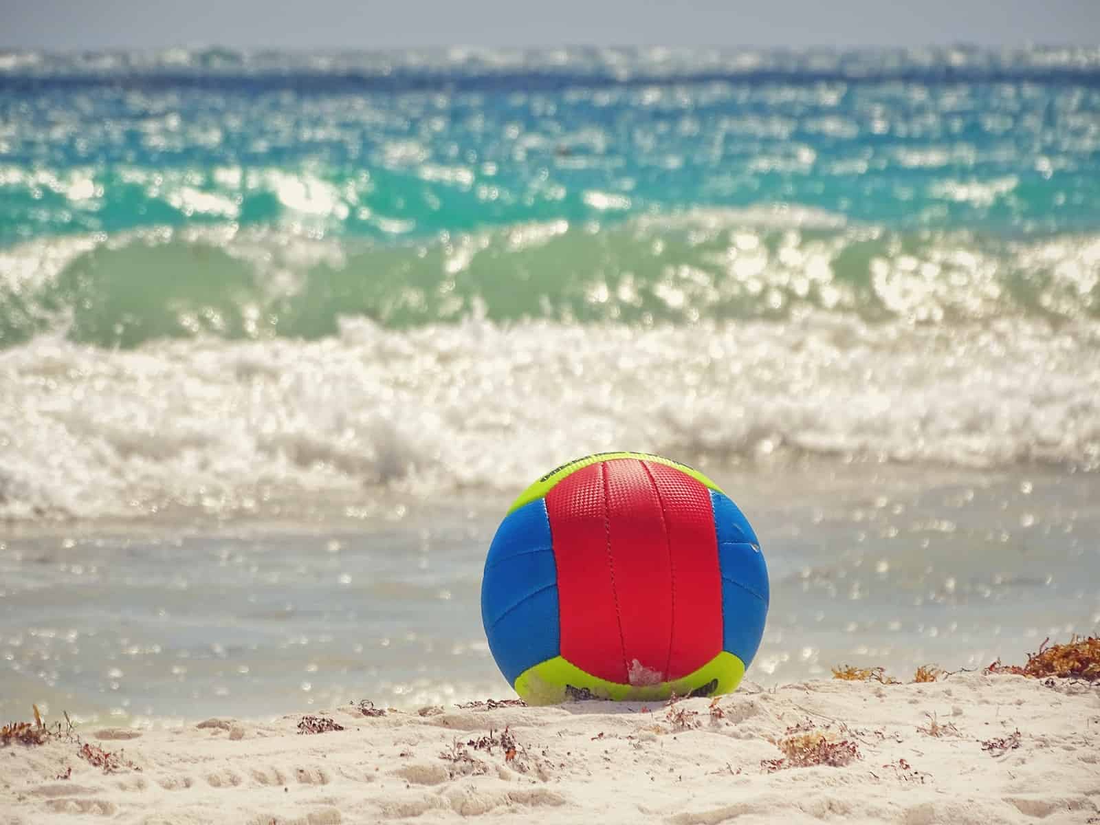 blue, red, and green volleyball in the beach during daytime