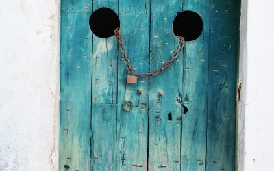 teal wooden door with gray chain and brown padlock